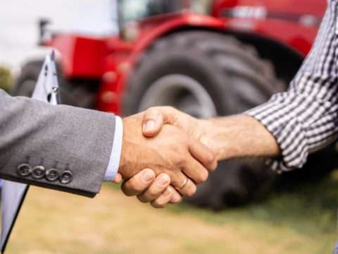Buying new tractor agricultural machine Buyer and dealer handshake at tractor dealership