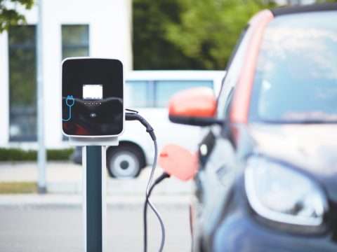 An electric vehicle recharging at a station after getting repaired with the help of a vehicle protection plan similar to what Veritas Global Protection offers.