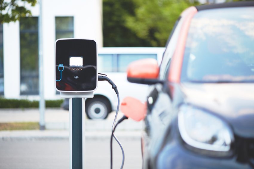 An electric vehicle recharging at a station after getting repaired with the help of a vehicle protection plan similar to what Veritas Global Protection offers.