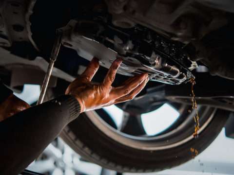 Car mechanic drain the old automatic transmission fluid (ATF) or gear oil at car garage for changing the oil in a gear box of car engine